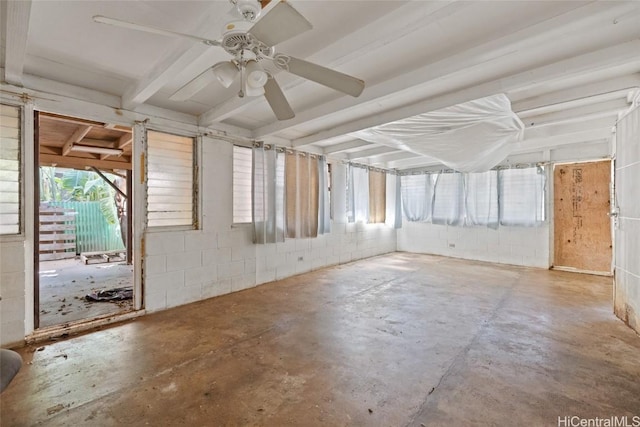 spare room with ceiling fan, concrete block wall, and unfinished concrete floors