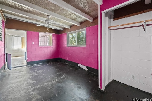 basement featuring ceiling fan and concrete block wall