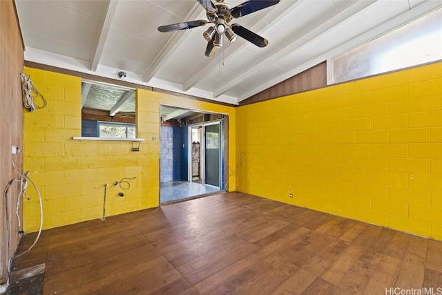 empty room featuring vaulted ceiling with beams, dark wood-style flooring, a ceiling fan, and concrete block wall