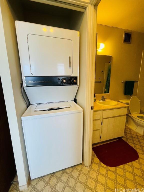 laundry room with stacked washer / dryer, visible vents, a sink, and light floors