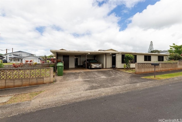 view of front of house with an attached carport, driveway, and fence