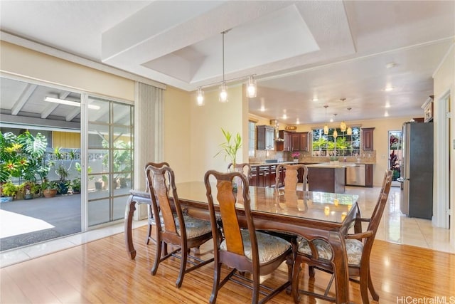 dining area featuring a raised ceiling and light wood-style floors