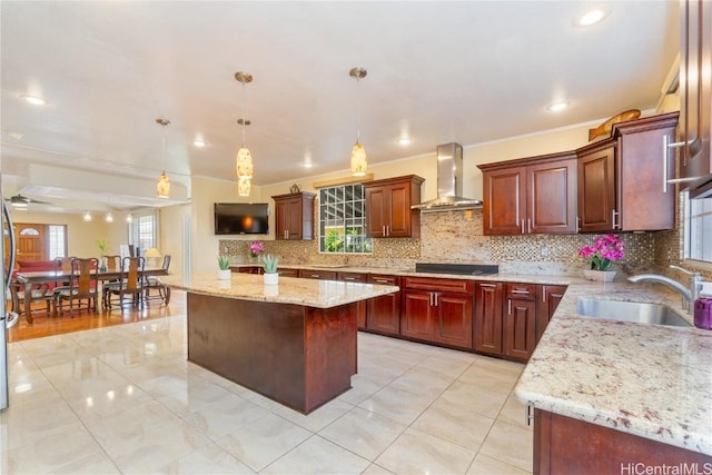 kitchen featuring wall chimney exhaust hood, tasteful backsplash, a kitchen island, and a sink