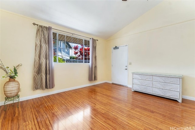 empty room with lofted ceiling, baseboards, and wood finished floors