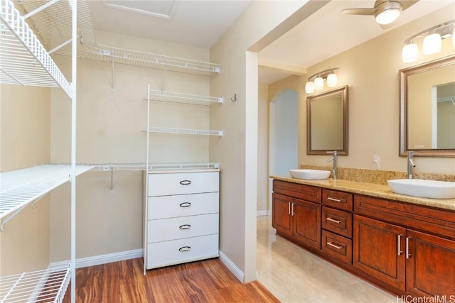 full bath featuring double vanity, ceiling fan, a sink, and wood finished floors