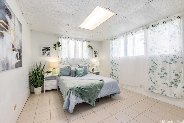 bedroom featuring a drop ceiling and light tile patterned floors