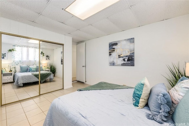 bedroom with a closet, a drop ceiling, and tile patterned floors