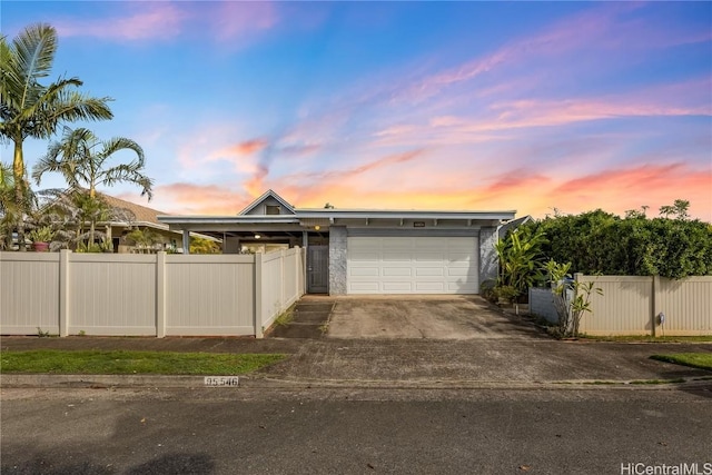 view of front of house with an attached garage, fence private yard, and driveway