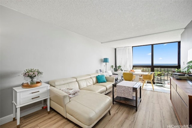 living room featuring light wood-type flooring, floor to ceiling windows, and a textured ceiling