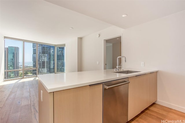 kitchen featuring a sink, light countertops, light wood-type flooring, expansive windows, and dishwasher