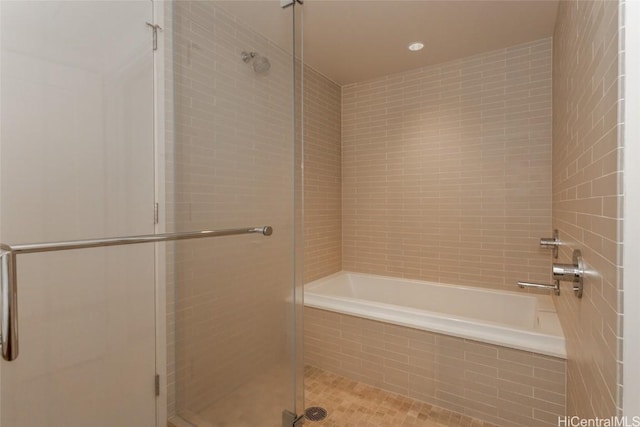 bathroom featuring tiled shower and tiled tub