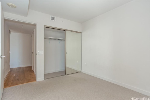 unfurnished bedroom featuring carpet floors, a closet, visible vents, and baseboards