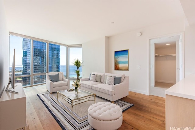 living room featuring baseboards, floor to ceiling windows, and light wood-style floors