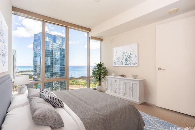 bedroom with carpet, floor to ceiling windows, multiple windows, and a water view