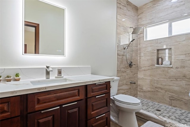 full bath featuring toilet, tiled shower, and vanity