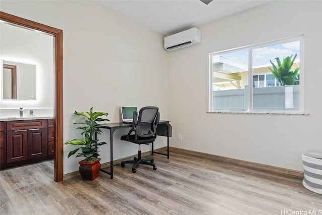 office area featuring an AC wall unit, light wood finished floors, and baseboards