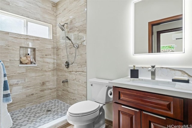 bathroom with toilet, tiled shower, and vanity