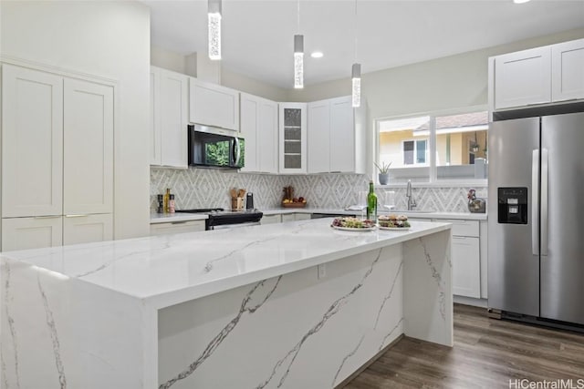 kitchen with white cabinets, light stone counters, stainless steel appliances, and decorative light fixtures