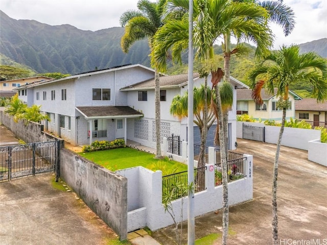 view of front of property featuring driveway, a fenced front yard, a gate, a mountain view, and stucco siding