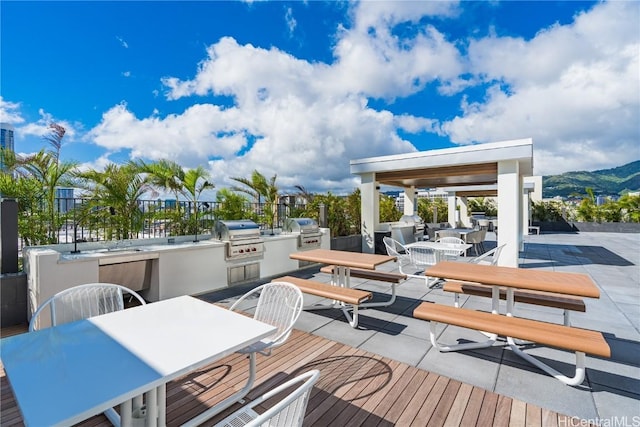 deck featuring exterior kitchen, outdoor dining area, a patio area, and a grill