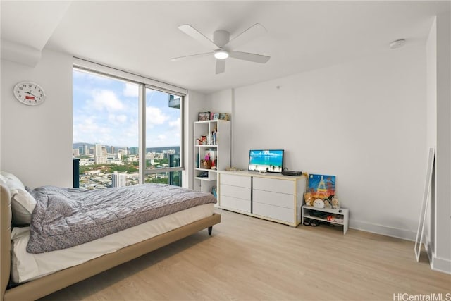 bedroom with light wood-style floors, expansive windows, baseboards, and a ceiling fan