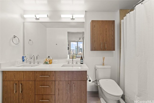 full bathroom with toilet, double vanity, and a sink