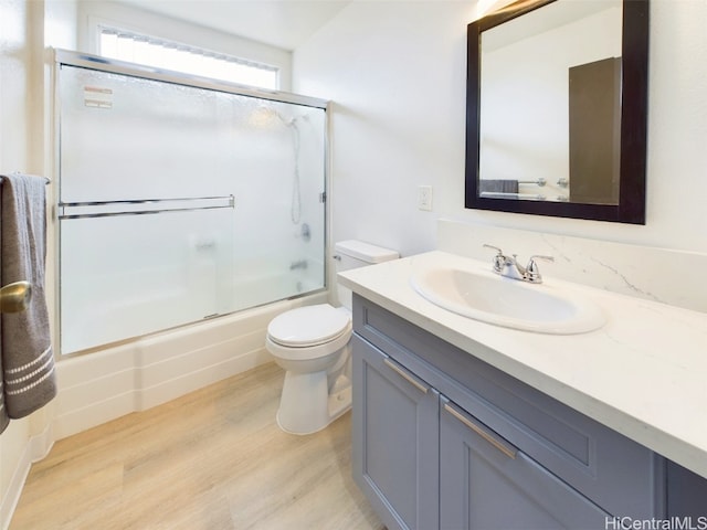 bathroom featuring enclosed tub / shower combo, vanity, toilet, and wood finished floors