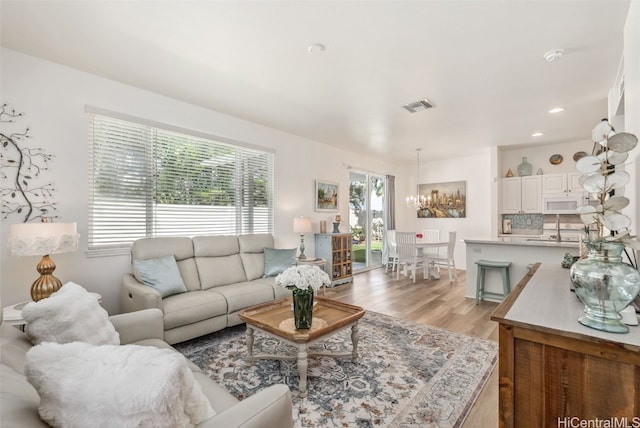 living room with light wood-type flooring, visible vents, and recessed lighting