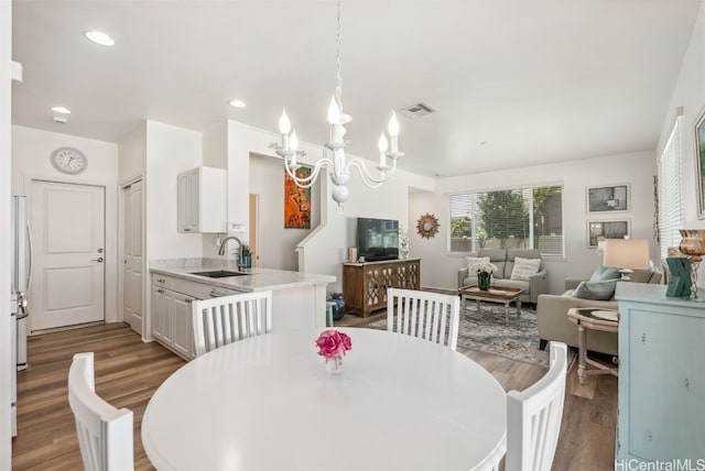 dining area featuring a chandelier, wood finished floors, visible vents, and recessed lighting