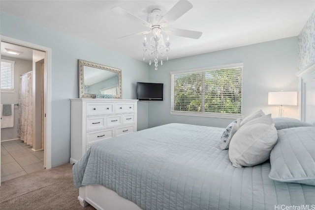 carpeted bedroom with ensuite bath and a ceiling fan