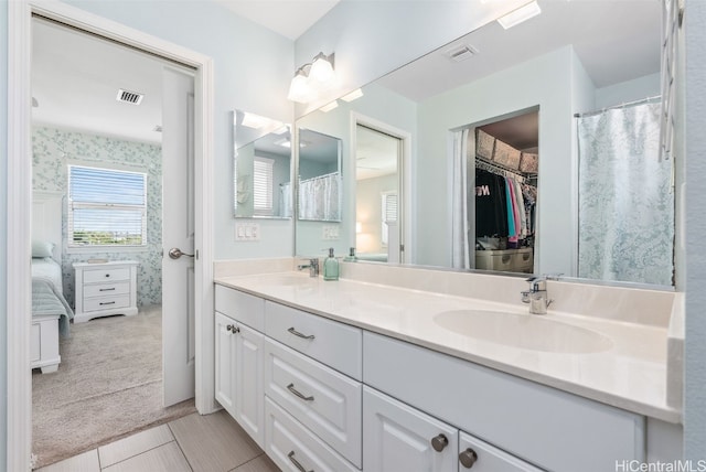 bathroom featuring double vanity, a sink, visible vents, and wallpapered walls