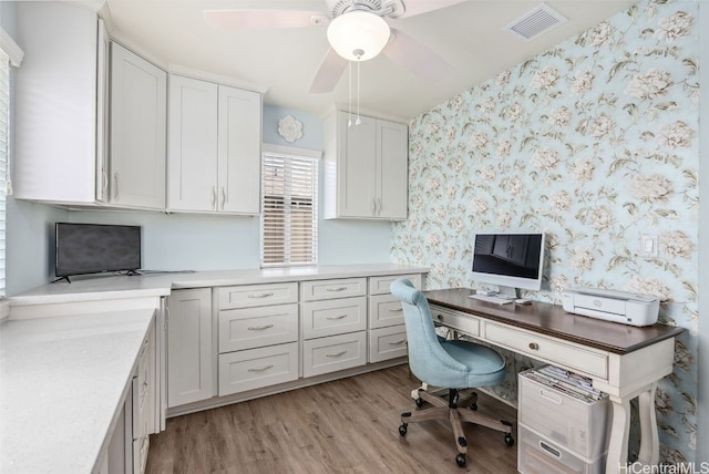 office area featuring light wood-type flooring, visible vents, ceiling fan, and wallpapered walls