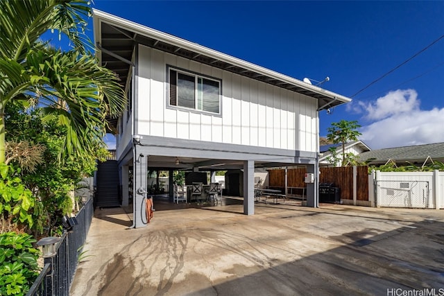 view of front of home featuring fence, driveway, outdoor dining area, a carport, and a patio area