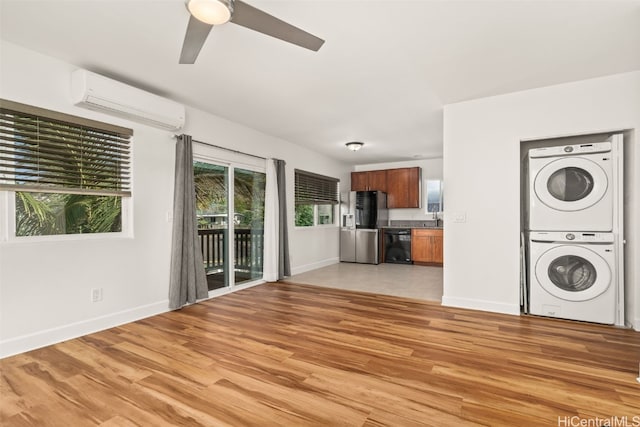 interior space featuring an AC wall unit, baseboards, stacked washer and clothes dryer, and light wood finished floors