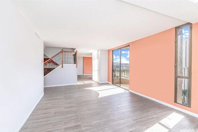311 Ohua Ave Unit Ph D, Honolulu, HI 96815 - spare room with visible vents, wood finished floors, stairway, a wall of windows, and baseboards