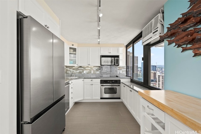 kitchen featuring glass insert cabinets, white cabinetry, appliances with stainless steel finishes, and decorative backsplash