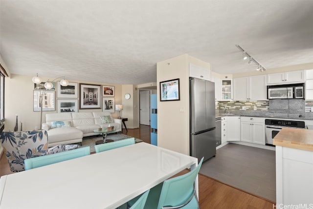 kitchen featuring stainless steel appliances, backsplash, dark wood-type flooring, open floor plan, and white cabinetry