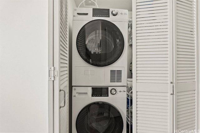 clothes washing area featuring stacked washer and dryer and laundry area