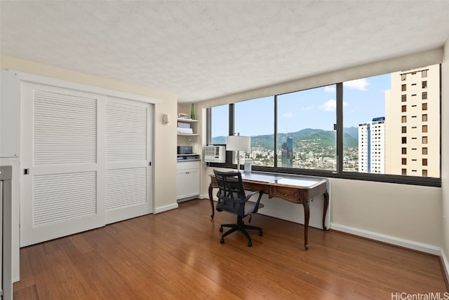 office space with a mountain view, a textured ceiling, baseboards, and wood finished floors