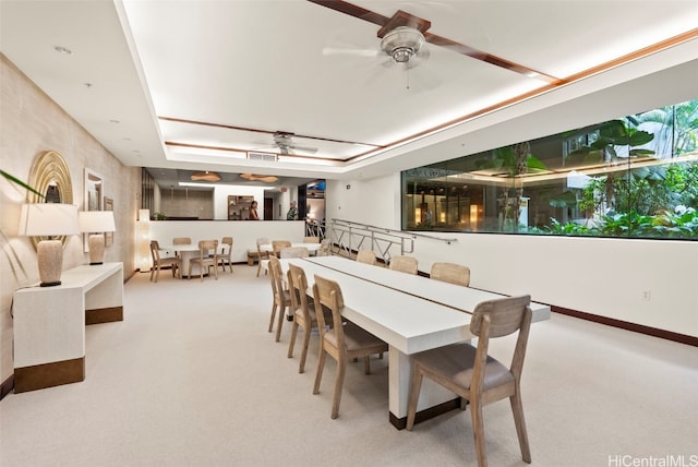 carpeted dining room featuring visible vents, a tray ceiling, and a ceiling fan