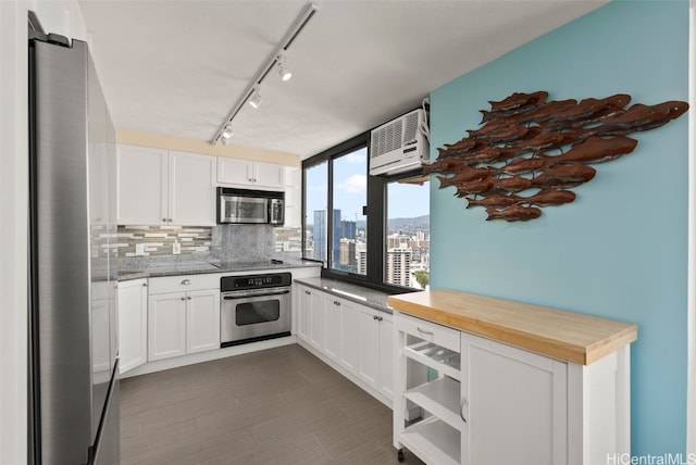 kitchen featuring a view of city, backsplash, appliances with stainless steel finishes, white cabinetry, and a wall mounted air conditioner