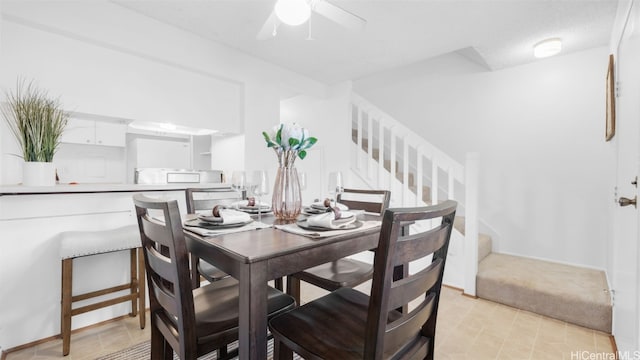 dining area featuring ceiling fan and stairs