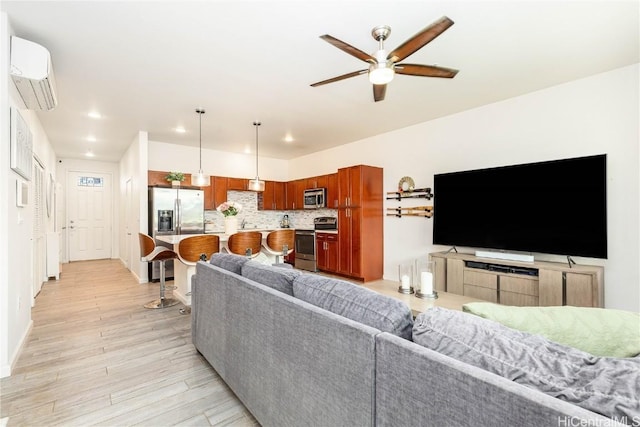 living room with baseboards, a wall unit AC, ceiling fan, light wood-style floors, and recessed lighting