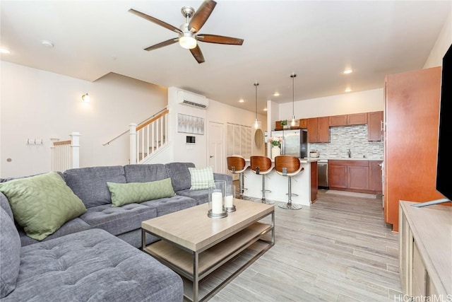 living room with light wood-style flooring, recessed lighting, a ceiling fan, an AC wall unit, and stairway