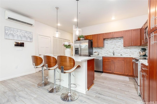 kitchen featuring a breakfast bar, a sink, an AC wall unit, appliances with stainless steel finishes, and decorative backsplash