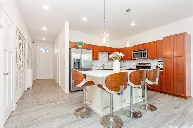 kitchen featuring light countertops, appliances with stainless steel finishes, light wood-type flooring, and backsplash