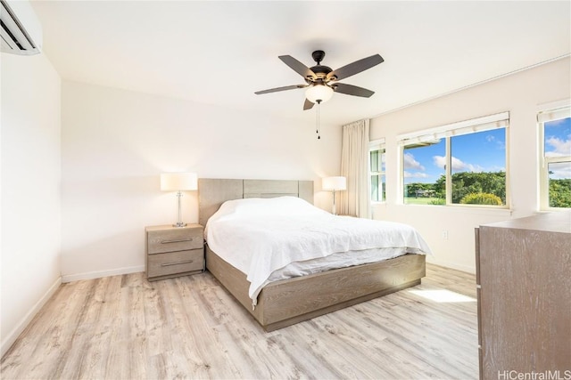 bedroom with ceiling fan, baseboards, wood finished floors, and a wall mounted AC