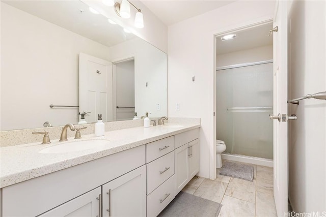 bathroom with a sink, a shower stall, toilet, and double vanity