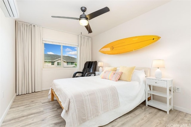 bedroom with ceiling fan, a wall mounted AC, wood finished floors, and baseboards