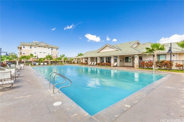 community pool with a patio area and fence